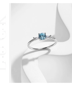 Macro detail of silver ring with round blue gemstone and tapered baguette diamonds