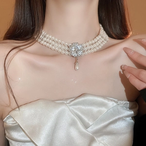 Close-up of triple-layer pearl choker with floral crystal pendant and teardrop pearl detail