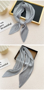 Detailed view of grey pleated silk scarf featuring delicate zigzag edges and metallic texture