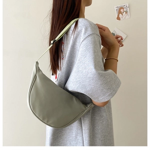 Sage green crescent hobo bag shown on shoulder, highlighting its sleek half-moon shape