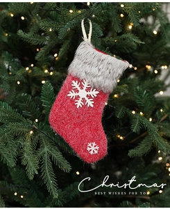 Detail of red knit Christmas stocking with gray faux fur trim and white snowflake accents