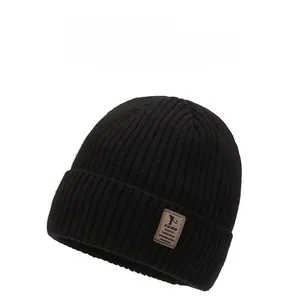 Detail of black ribbed knit beanie featuring a premium brown leather brand logo patch