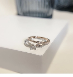Macro shot of silver and rose gold rings with emerald-cut stones on a white display