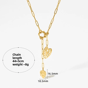 Détail de pendentifs feuille de monstera dorés sur un collier chaîne à trombones