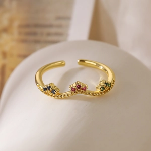 Macro shot of gold-plated crown ring with colorful cubic zirconia on white pedestal