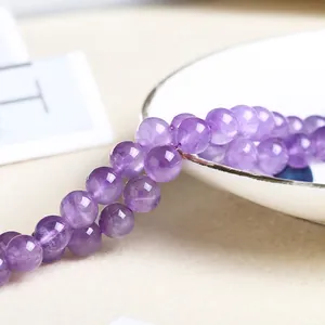 Polished natural purple amethyst round beads for DIY jewelry making on white ceramic plate