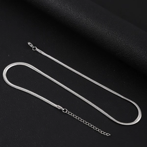 Détail d'un collier chaîne serpent argentée avec fermoir mousqueton sur cuir noir texturé