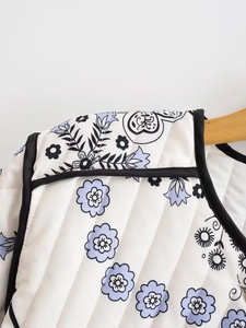 Close-up of quilted floral cotton jacket featuring blue patterns and black piped edges
