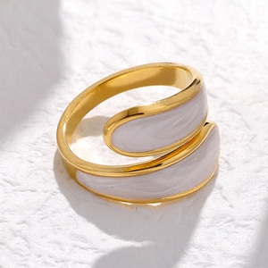 Close-up of golden stainless steel ring with white enamel drip detail on white stone