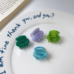 Detail of four colorful acetate heart hair clips with marble texture on ceramic plate