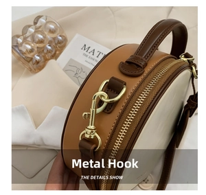 Detail showing high-quality gold metal hooks and contrast stitching on the round bag