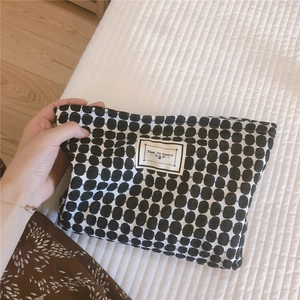 Detail of checkered cotton makeup bag with 'TIME TO PARTY' label in hand-held shot