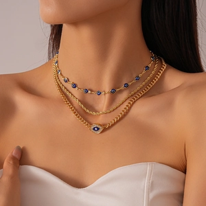 Detailed close-up of a three-layer gold evil eye necklace with crystals on a model