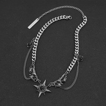 Macro detail of gothic silver necklace with star pendant and wing charms on black background