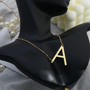 Detail of gold letter A pendant necklace on black bust with luxury aesthetic decor