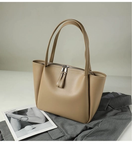 Detail of light brown leather tote bag with silver double zippers and long handles
