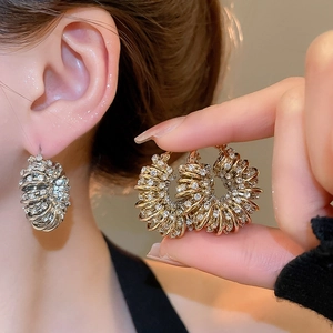 Detail of twisted pavé rhinestone U-shaped earrings in gold and silver finishes