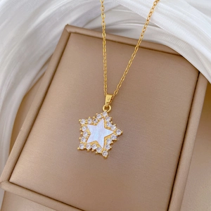 Detailed close-up of a gold star necklace with shell inlay and crystals on satin background
