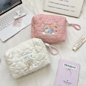 Detail of pink and white heart-quilted cosmetic bags with cartoon puppy embroidery