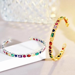 Close-up of gold and silver open bracelets with colorful geometric zircon gemstones