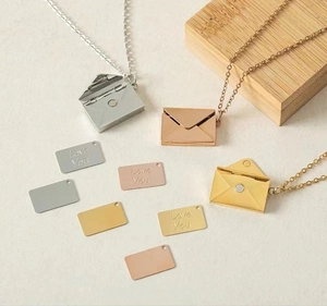 Detailed view of silver, gold, and rose gold envelope pendants with Love You inserts
