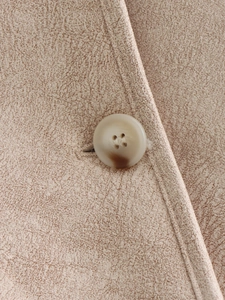 Close-up of marble pattern button and fleece-lined suede texture on a beige jacket