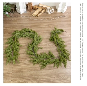 Realistic green PE Christmas garland decoration displayed on a light wood floor