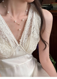 Close-up of elegant Y-shaped pearl necklace with gold chain worn on a model