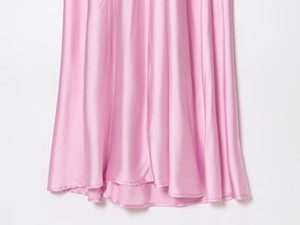 Detailed view of the smooth pink satin dress hem showing the silky fabric and drape