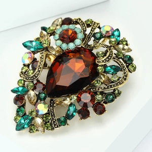 Close-up of vintage baroque brooch featuring amber teardrop gem and colored rhinestones