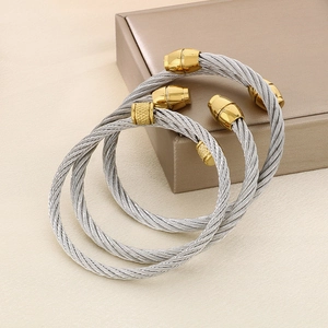 Detailed macro view of three gold and silver cable wire cuff bracelets in twisted steel