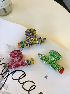 Detail of colorful acrylic pencil hair claws with candy tones on a white book