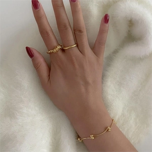 Close-up of a 925 sterling silver twisted ring and gold ball chain bracelet on a hand