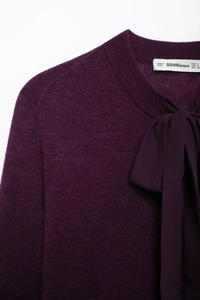 Détail d'un haut en maille violet avec col rond et nœud papillon en ruban de soie