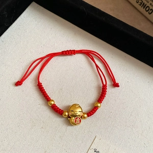 Vue détaillée du bracelet tressé rouge avec breloque serpent dorée et symbole de chance