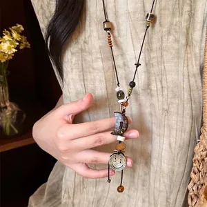 Détail du collier de perles avec pendentif lune et breloque rétro sur cordon ciré