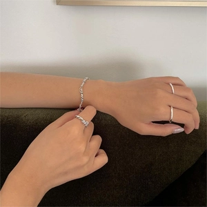 Detailed view of sterling silver twisted rope chain bracelet and minimalist stacked rings