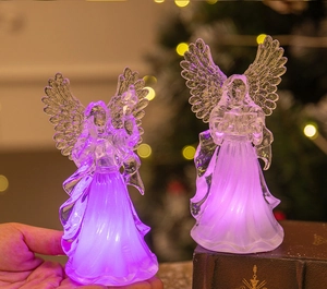 Close-up of a crystal acrylic LED angel lamp glowing on a book with Christmas decor