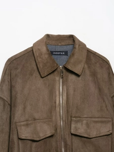 Detailed close-up of dark brown suede jacket with silver zipper and classic lapel collar