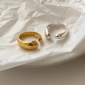 Detailed view of minimalist gold and silver teardrop open rings on white textured paper