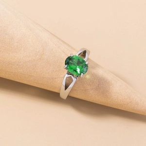 Macro shot of silver ring with green oval gemstone on a wooden display stand