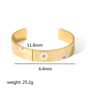 Detail view of enamel daisy pattern on gold open bangle with 11.8mm width specs