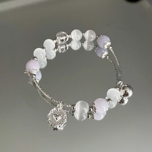 Detailansicht der Katzenaugenperlen und des Herzanhängers am eleganten Armband