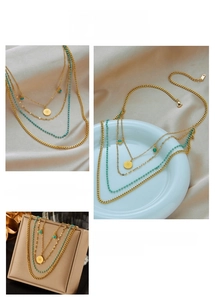 Détail d'un collier doré multi-rangs avec pendentif pièce étoile et perle turquoise
