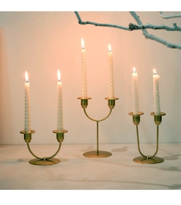 Close-up of golden double-head metal candle holders with white spiral candles