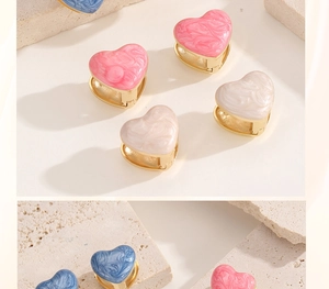 Detail of heart-shaped earrings with marble enamel and gold-plated finish on stone base