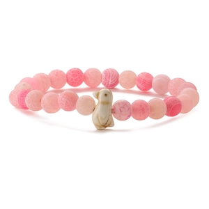 Detailed view of pink beaded stretch bracelet with natural stone and a cute penguin charm