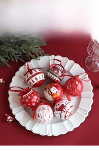 Detailed view of patterned Christmas foam balls with red ribbons on a white decorative plate