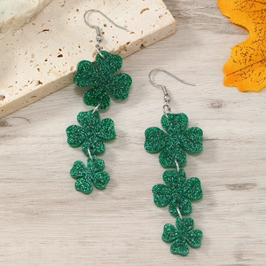 Detail of green glitter shamrock dangle earrings on a natural stone background