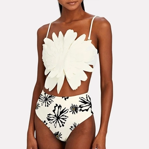 Detail of 3D laser-cut flower decoration on white bikini top with high-waisted floral bottom